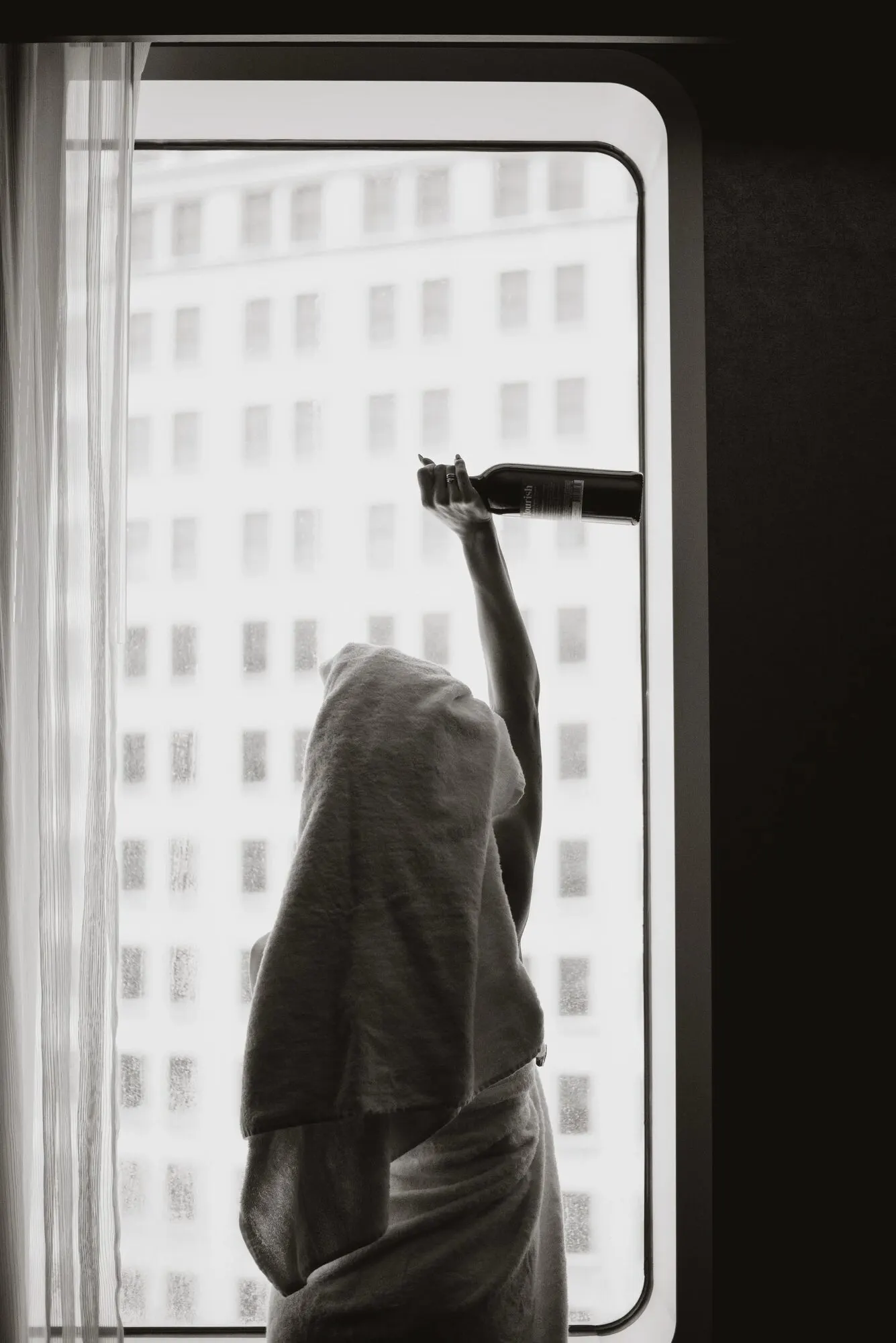 Silhouette against a window filled with the repeating window grid of an office tower.