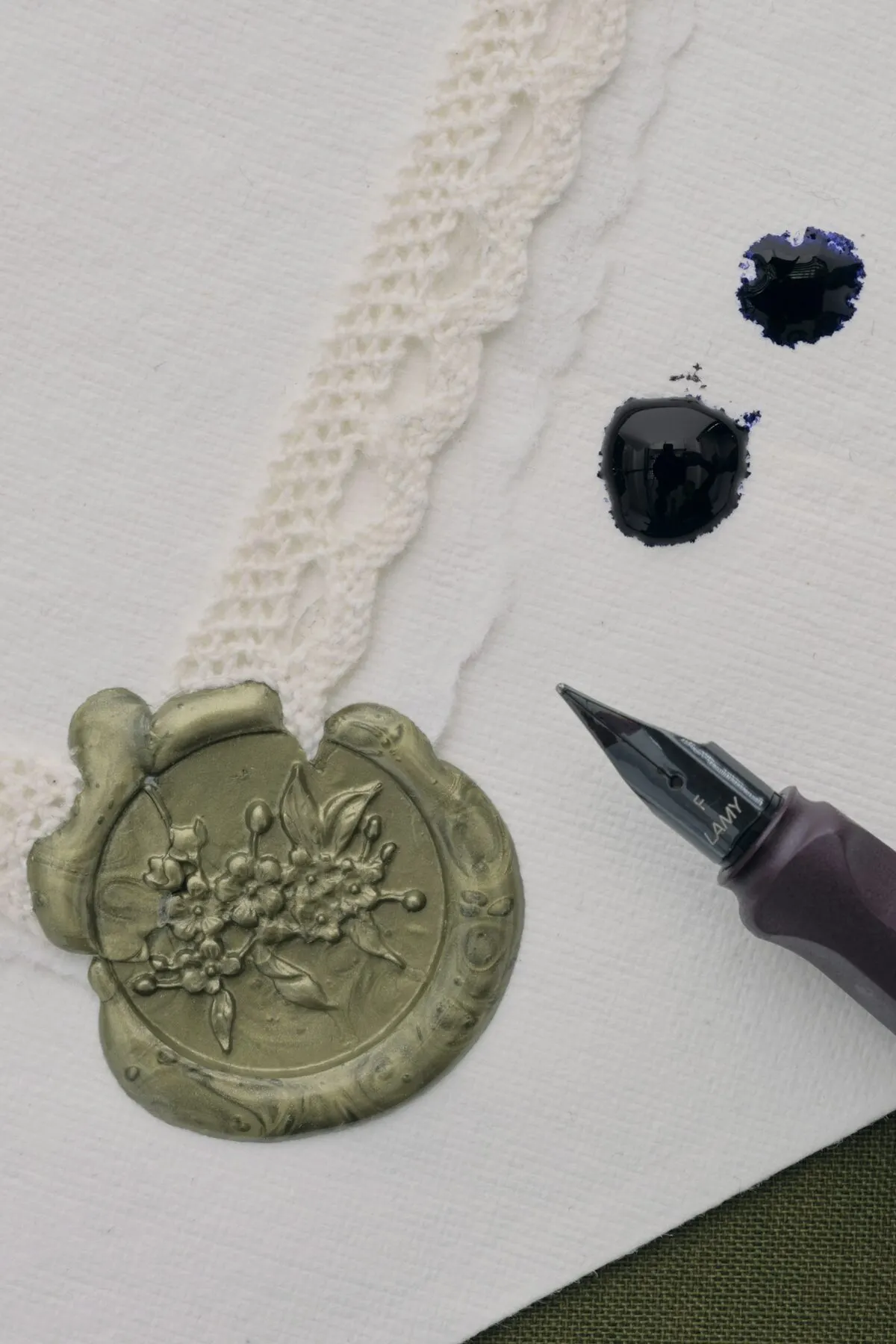 A wax seal and a fountain pen resting on heavy paper.