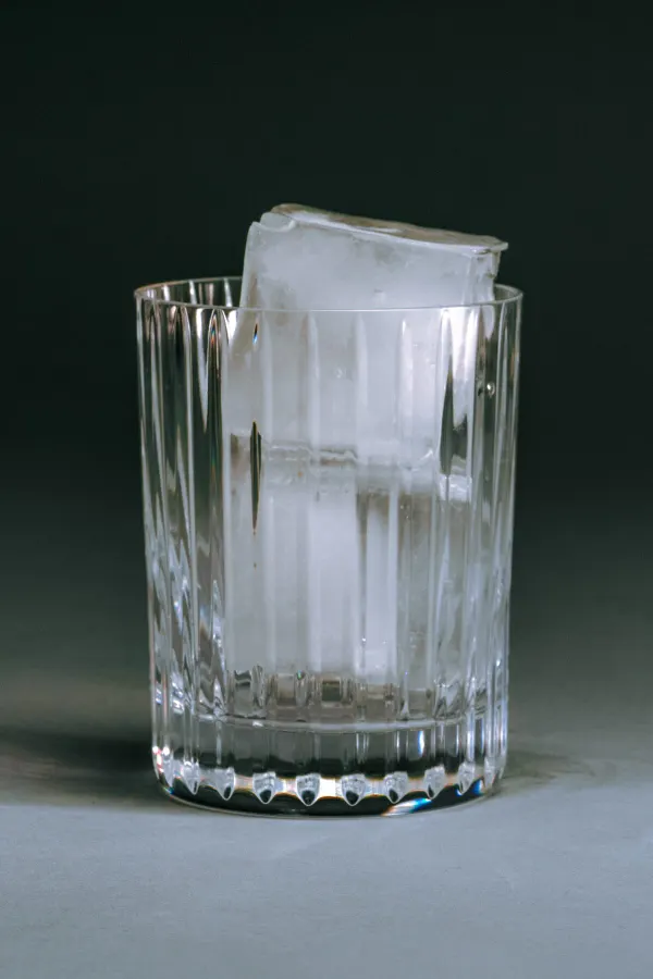 A cut crystal glass standing on a deep green surface.