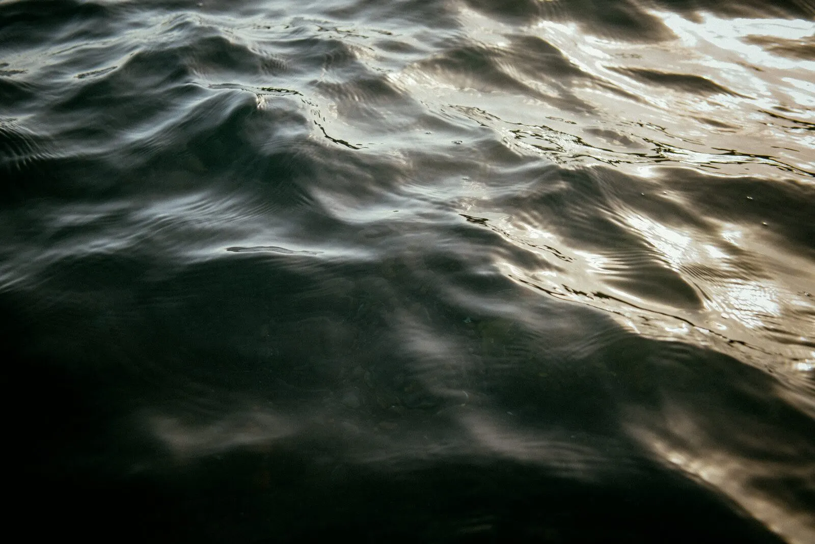 Dark water with a thin band of light across it, wide frame.